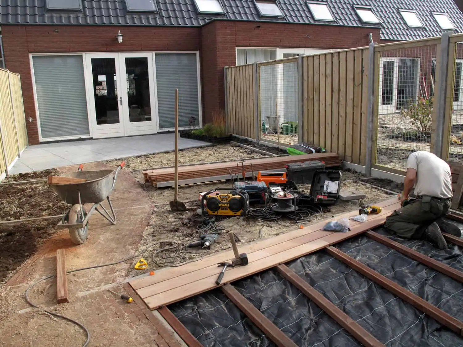 Hovenier legt een houten terras aan in een achtertuin