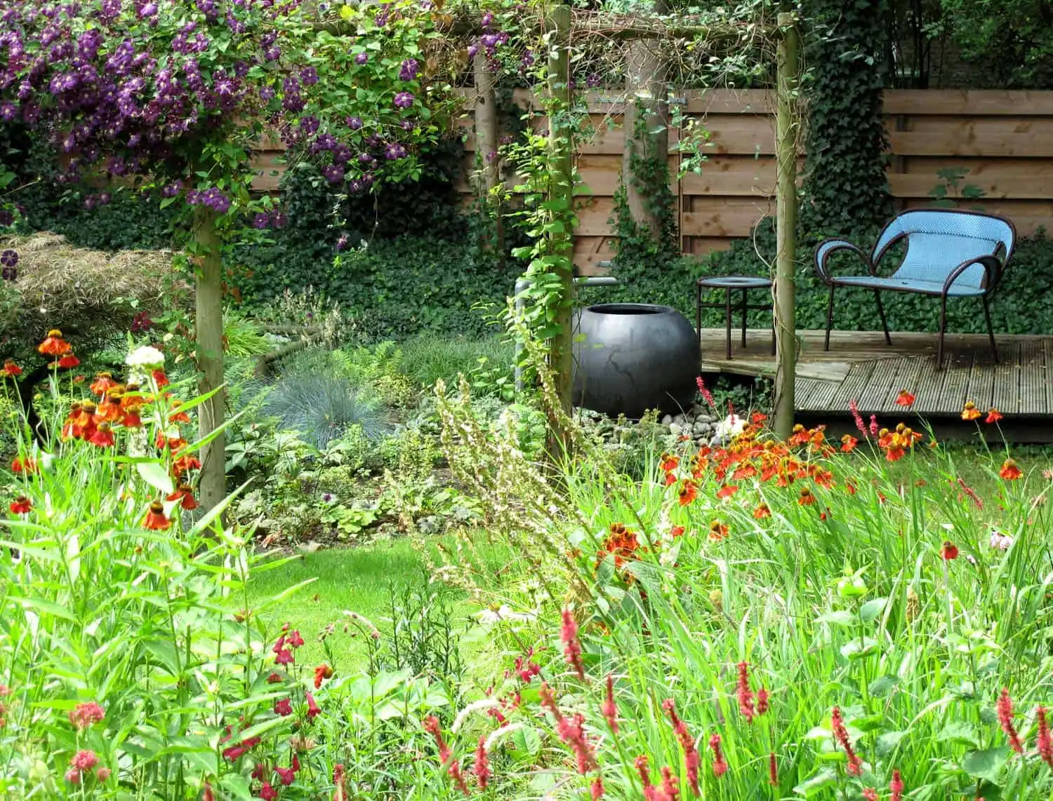 Rood oranje prairiebeplanting voor een terrasje met waterelement