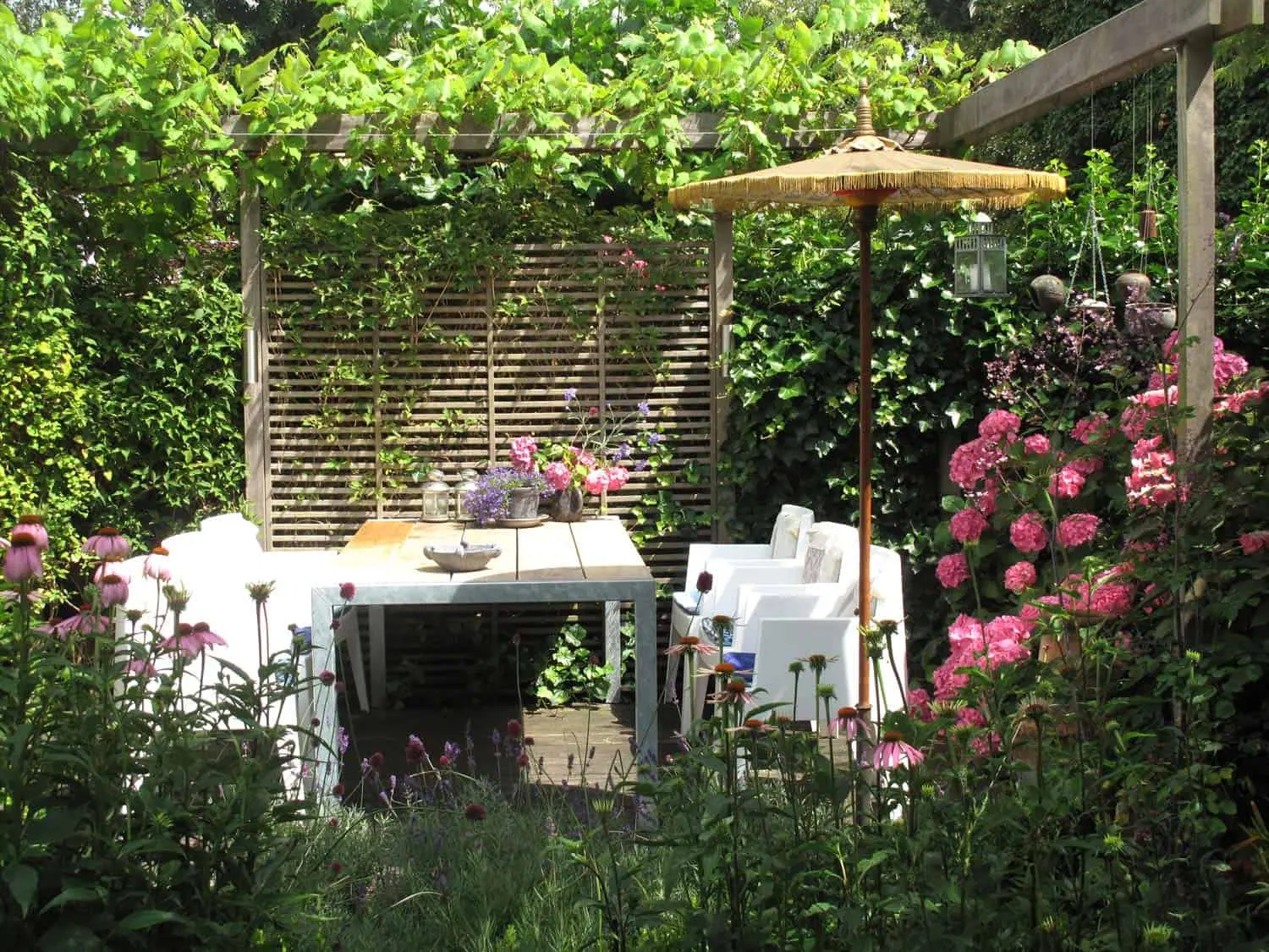 Oosterse parasol bij eettafel met roze hortensia’s rondom