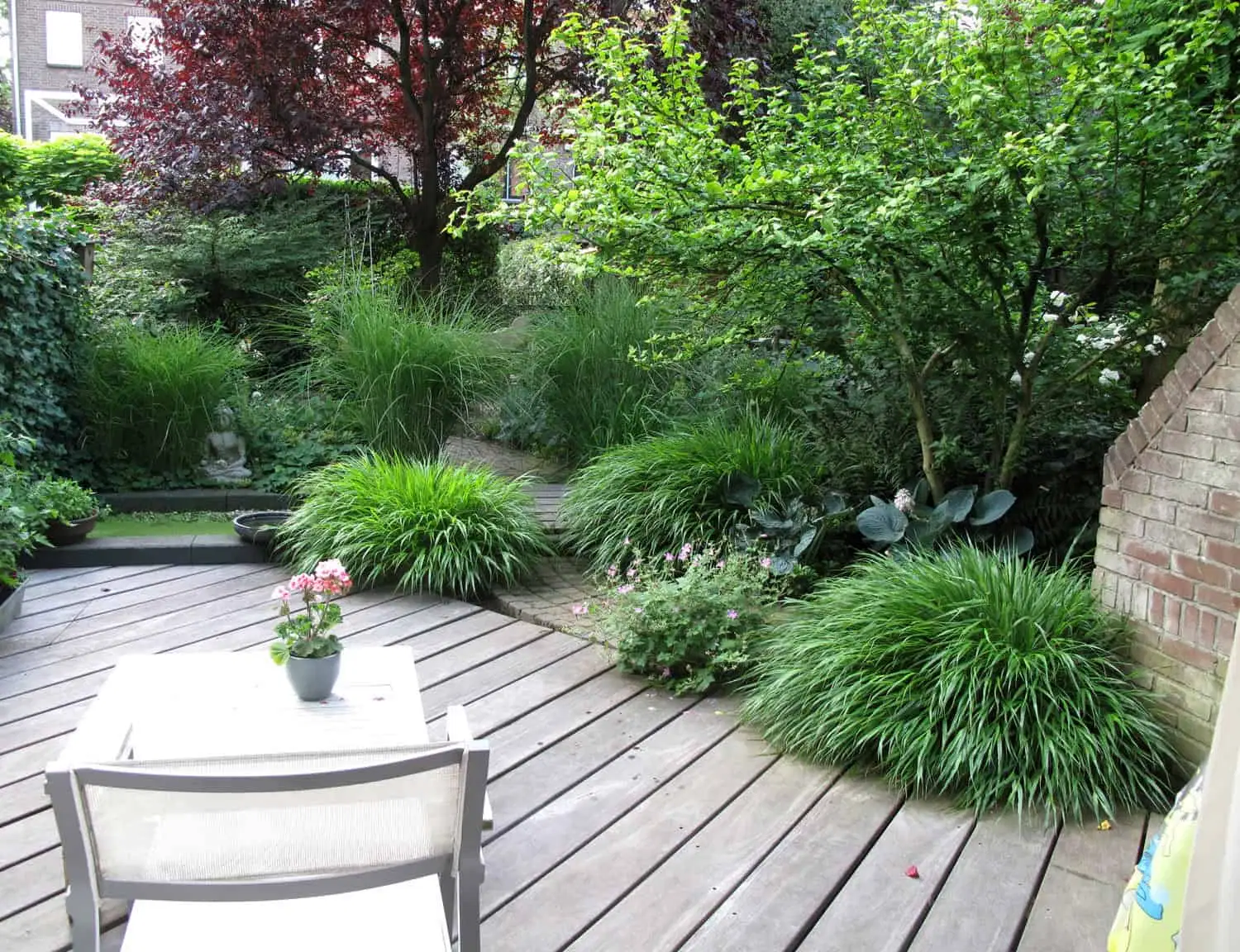 Houtenvlonder met zicht op boeddha beeld tussen grassen