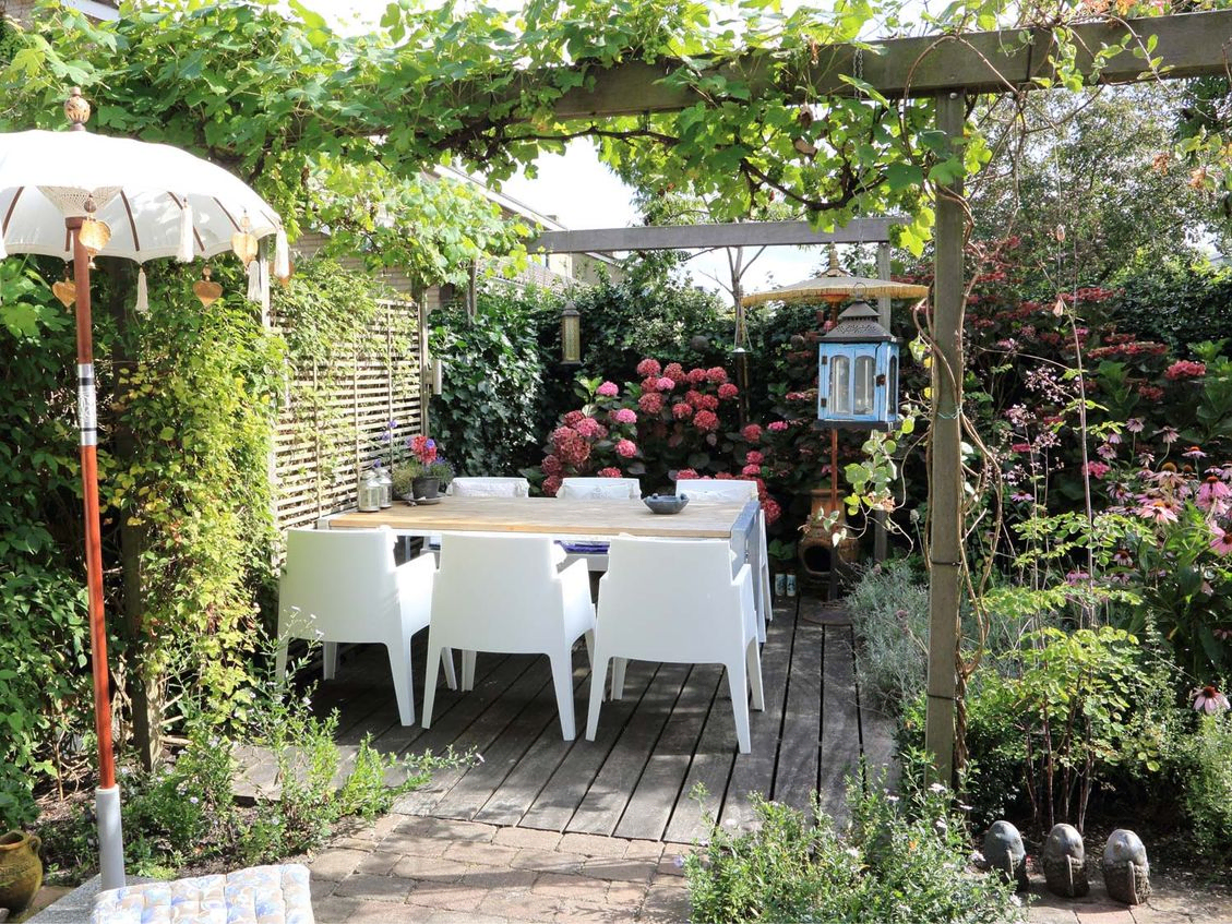 stads-tuinontwerp mozaiek in nijmegen van het buitenland met eettafel onder pergola's met parasolletje op voorgrond
