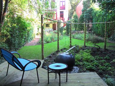 stads-tuinontwerp prairie in het bos in nijmegen van het buitenland met loungeterras in een door een gebogen pergola begrensde bostuin