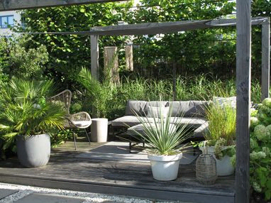 stads-tuinontwerp tuin in terrassen in nijmegen van het buitenland met loungebank omringd door potten met exotische planten