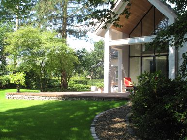 landschaps-tuinontwerp groene oase in nijmegen van het buitenland met een moderne veranda met verhoogd terras met keerwand