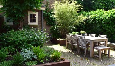 stads-tuinontwerp levensloop in nijmegen van het buitenland met een buiten eetterras tussen verhoogde plantenborder en waterloop