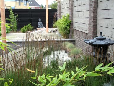stads-tuinontwerp koi tuin in nijmegen van het buitenland met japanse lantaarn in beplanting voor een verhoogde houten loopbrug