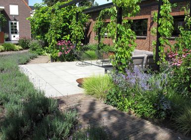 landschaps-tuinontwerp panta rei in nijmegen van het buitenland met loungeterras overdekt met druiven over 3 zwarte pergola's