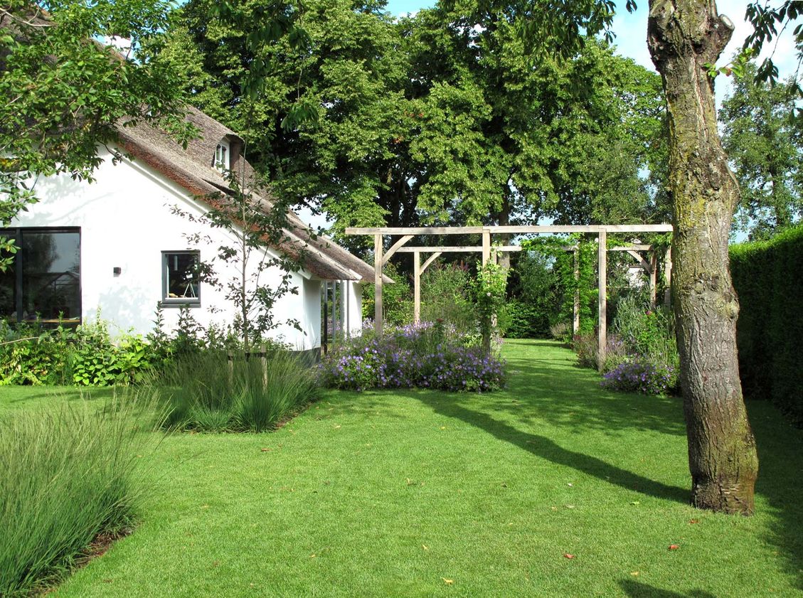 landschaps-tuinontwerp eten uit je tuin in nijmegen van het buitenland met een zichtas onder een boom door naar 2 pergola's