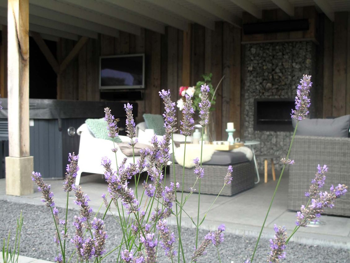 stads-tuinontwerp super lounge in nijmegen van het buitenland met een jacuzzi en loungeset bij de open haard onder de overkapping