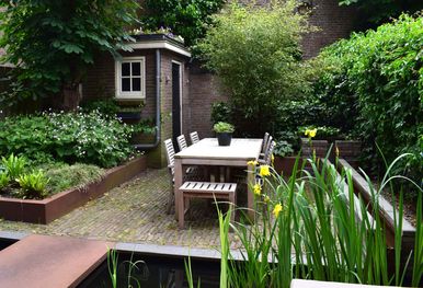 stads-tuinontwerp levensloop in nijmegen van het buitenland met een cortenstalen loopbrug over een strakke vijver met gele irissen