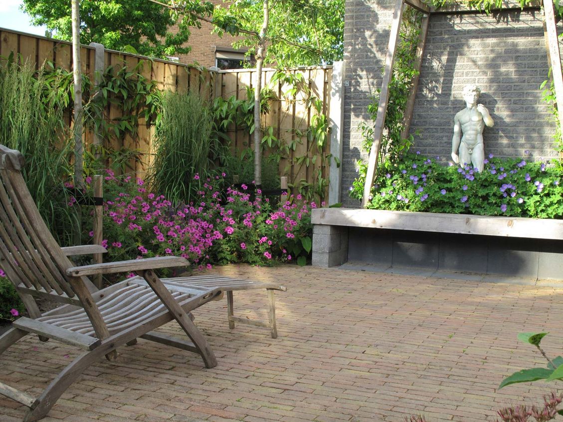 stads-tuinontwerp trapezium in nijmegen van het buitenland met ligstoel op trapeziumvormig terras uitkijkend op het prieel