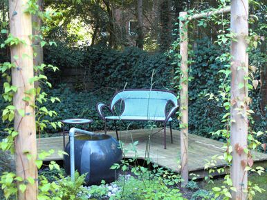 stads-tuinontwerp prairie in het bos in nijmegen van het buitenland met een loungeterras met blauw bankje voor een waterelement