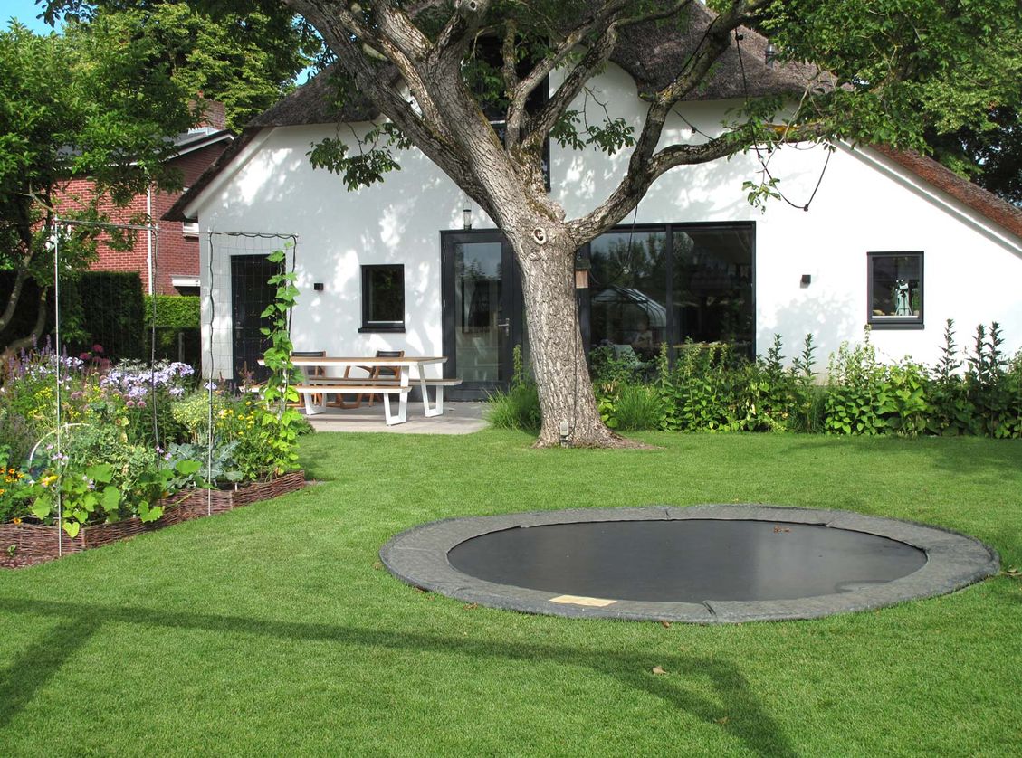 landschaps-tuinontwerp eten uit je tuin in nijmegen van het buitenland met een gazon met trampoline voor de achtergevel