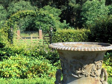 landschaps-tuinontwerp tuin in vorm in nijmegen van het buitenland met een koperen vaas die de blik leidt naar de boomgaard
