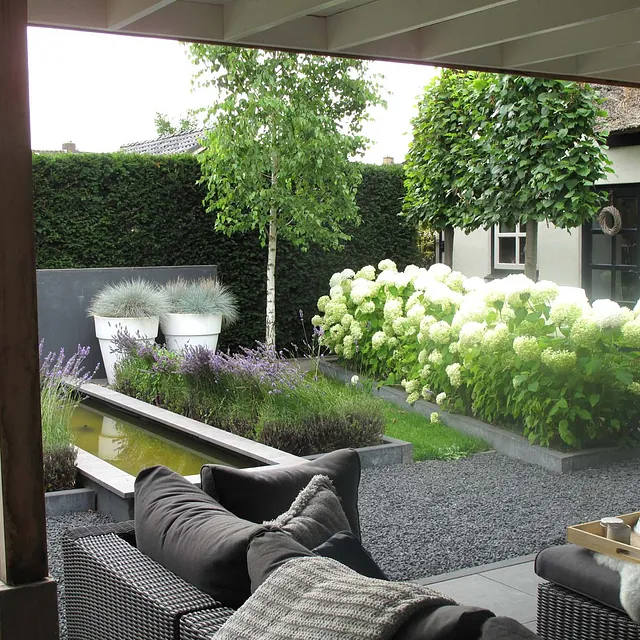 stads-tuinontwerp super lounge in nijmegen van het buitenland met een loungebank onder een overkapping uitkijkend op de vijvertuin