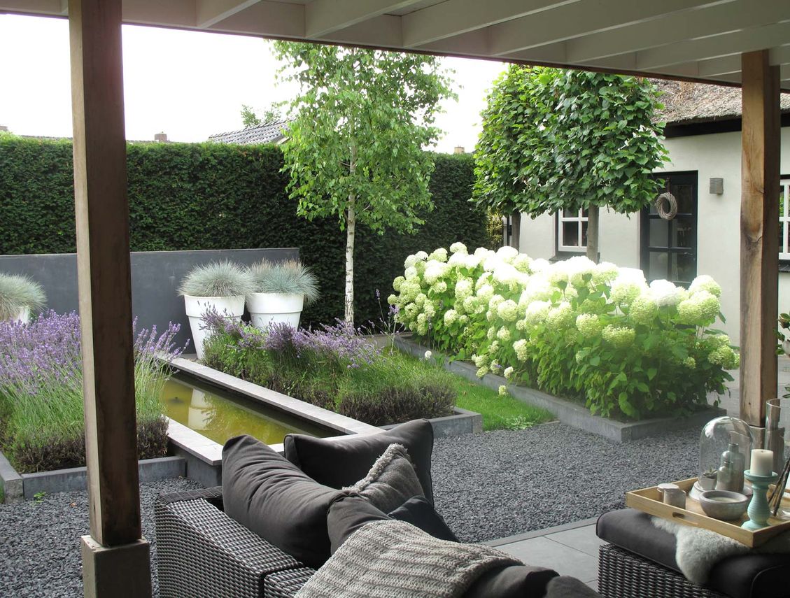 stads-tuinontwerp super lounge in nijmegen van het buitenland met een loungebank onder een overkapping uitkijkend op de vijvertuin